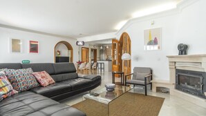 A modern living room with a black leather sofa, a glass coffee table, and a fireplace. - FU1 in Moncarapacho With 6 Bedrooms and 6 Bathrooms (Olhao)