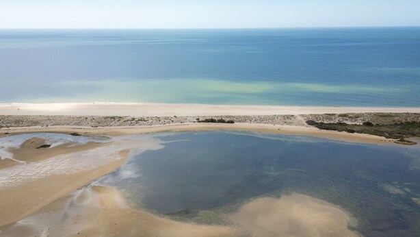 A beach with clear water, sandy shore, and sparse vegetation. - FU1 in Moncarapacho With 6 Bedrooms and 6 Bathrooms (Olhao)