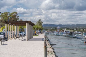 A waterfront promenade with a covered seating area, a row of parked cars, and a marina with boats. - FU1 in Moncarapacho With 6 Bedrooms and 6 Bathrooms (Olhao)