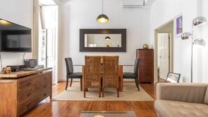 A modern living room with a flat-screen TV, wooden furniture, a glass coffee table, and a large mirror. - CR2 in Lisboa Ciudad (Lisbon)