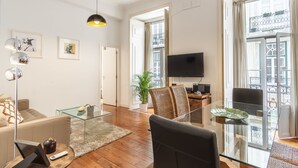 A modern living room with a sofa, a glass coffee table, a TV, and a large window with a view of a balcony. - CR2 in Lisboa Ciudad (Lisbon)