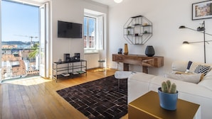 A modern living room with a sofa, a coffee table, a TV, and a view of the city. - BI1 in Lisboa Ciudad (Lisbon)