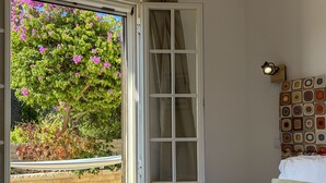 Une chambre avec une fenêtre, un radiateur, un lit avec des oreillers et un luminaire fixé au mur.