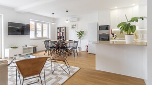 Una cocina moderna con comedor, armarios blancos y una planta grande en maceta.