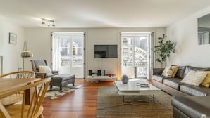 Una sala de estar con sofá, una mesa de centro, televisor y un comedor con sillas y mesa.