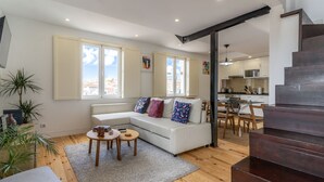 Una sala de estar moderna con un sofá blanco, una mesa de centro y una escalera que lleva a una cocina.