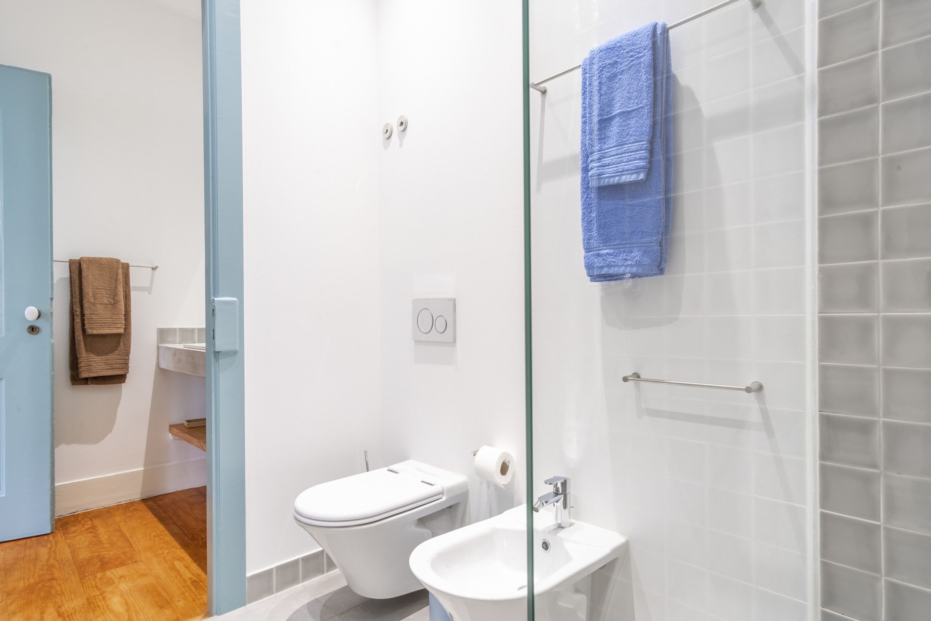 A modern bathroom with a glass shower enclosure, a toilet, and a sink.