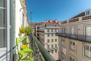 A balcony with a chair and potted plant, overlooking a row of buildings with traditional architecture and balconies. - PR2 in Lisboa Ciudad (Lisbon)