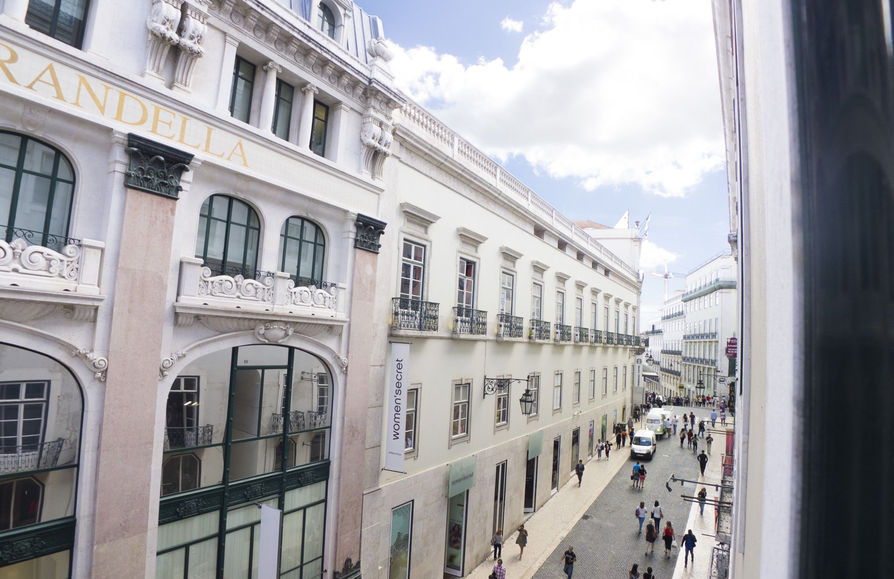 A historic building with ornate architecture, large windows, and a bustling street below.