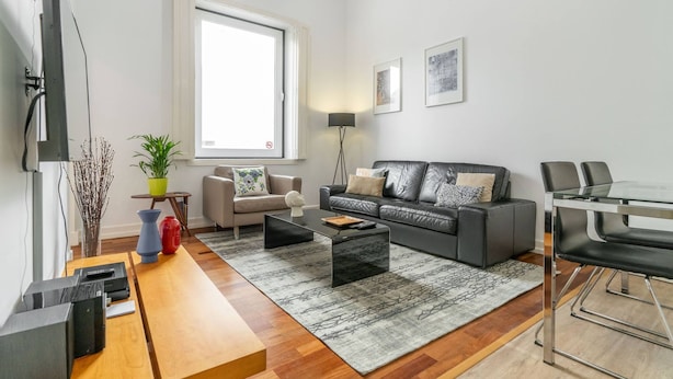 A modern living room with a sofa, coffee table, TV, and a dining area with chairs. - CH8 in Lisboa Ciudad (Lisbon)