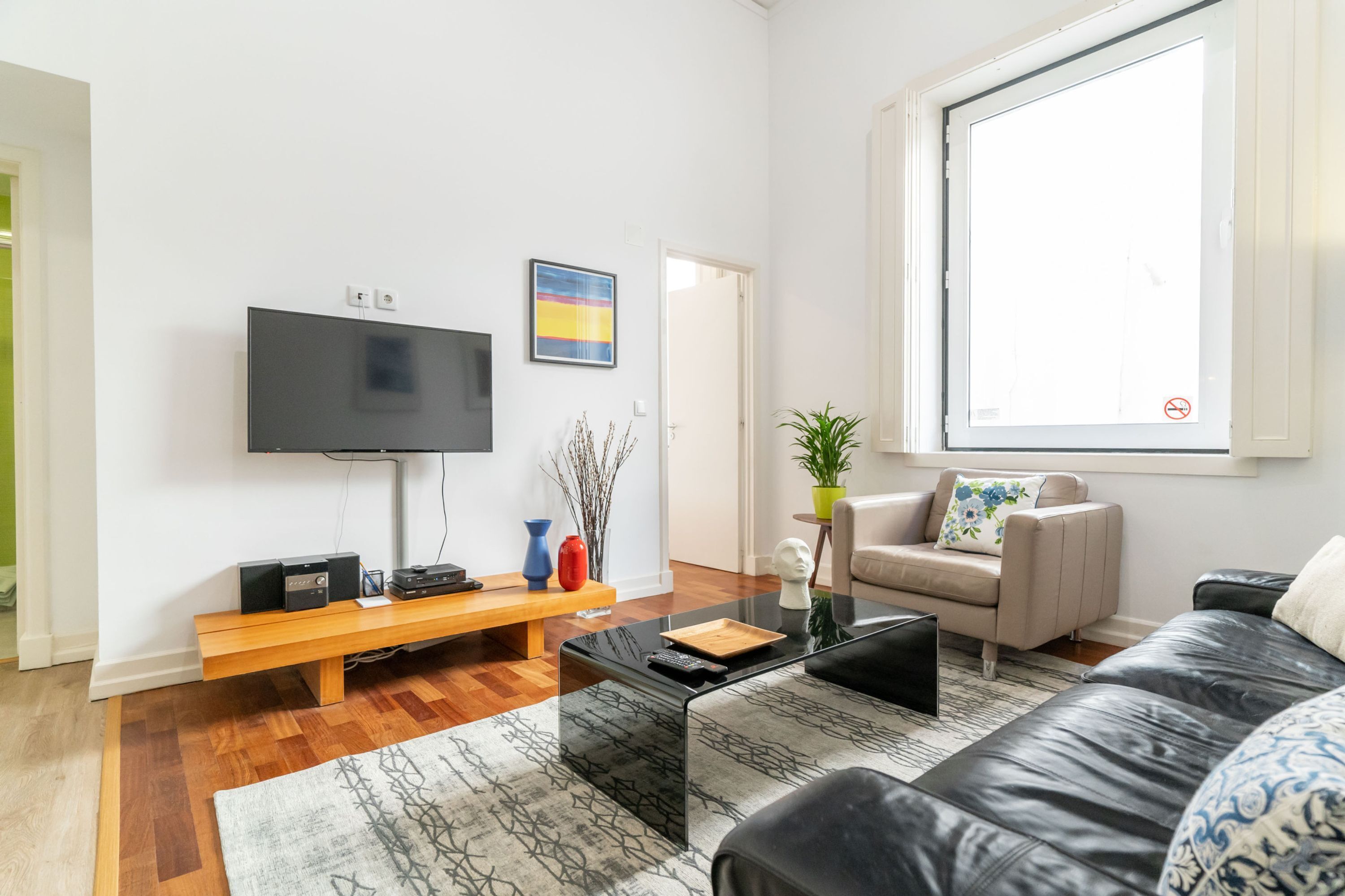 En stue med et fladskærms TV, en sofa, et sofabord og en bænk.