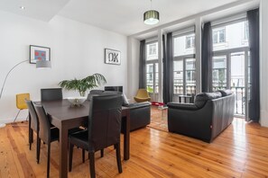 A modern living room with a dining table, chairs, a sofa, and a potted plant. - FI in Lisboa Ciudad With 2 Bedrooms and 1 Bathrooms (Lisbon)