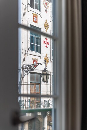 Eine Gebäudefassade mit Fenster, einer Straßenlaterne und einem Balkongeländer.
