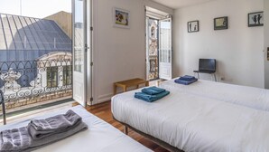A hotel room with two beds, a balcony, a television, and a small table. - CH1 in Lisboa Ciudad (Lisbon)
