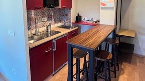 Uma cozinha moderna com armários vermelhos, bancada de madeira e um espaço de bar com banquetas.