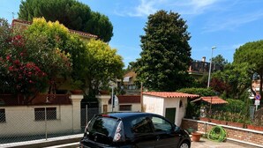 Um carro preto estacionado em um caminho de cascalho, com uma casa ao fundo.