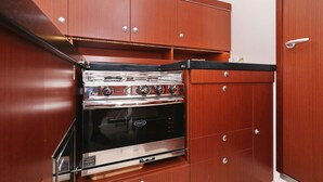 A compact kitchen with a built-in oven, wooden cabinets, and a stainless steel range hood. - Sun-Kissed Sailing Adventure in Zadar, Croatia (Biograd na moru)