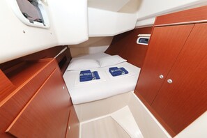 A compact cabin with a small bed, wooden cabinetry, and a window.