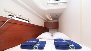 A narrow cabin with a bed, two towels, a window, and a shower head. - Sun-Kissed Sailing Adventure in Zadar, Croatia (Biograd na moru)