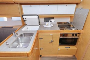 A compact kitchenette with a sink, stove, and storage cabinets. - Sibenik Sun and Beach Sailing Extravaganza: A Croatian Coastal Adventure (Vodice)