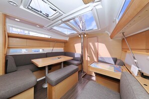 Un interior pequeño y bien iluminado, con una mesa, bancos y un tragaluz.
