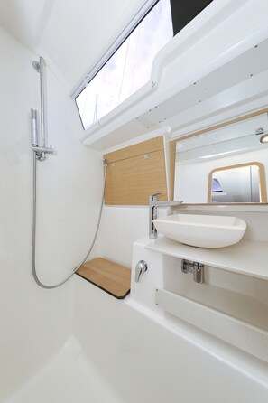 Un baño con tragaluz, lavamanos blanco y ducha.