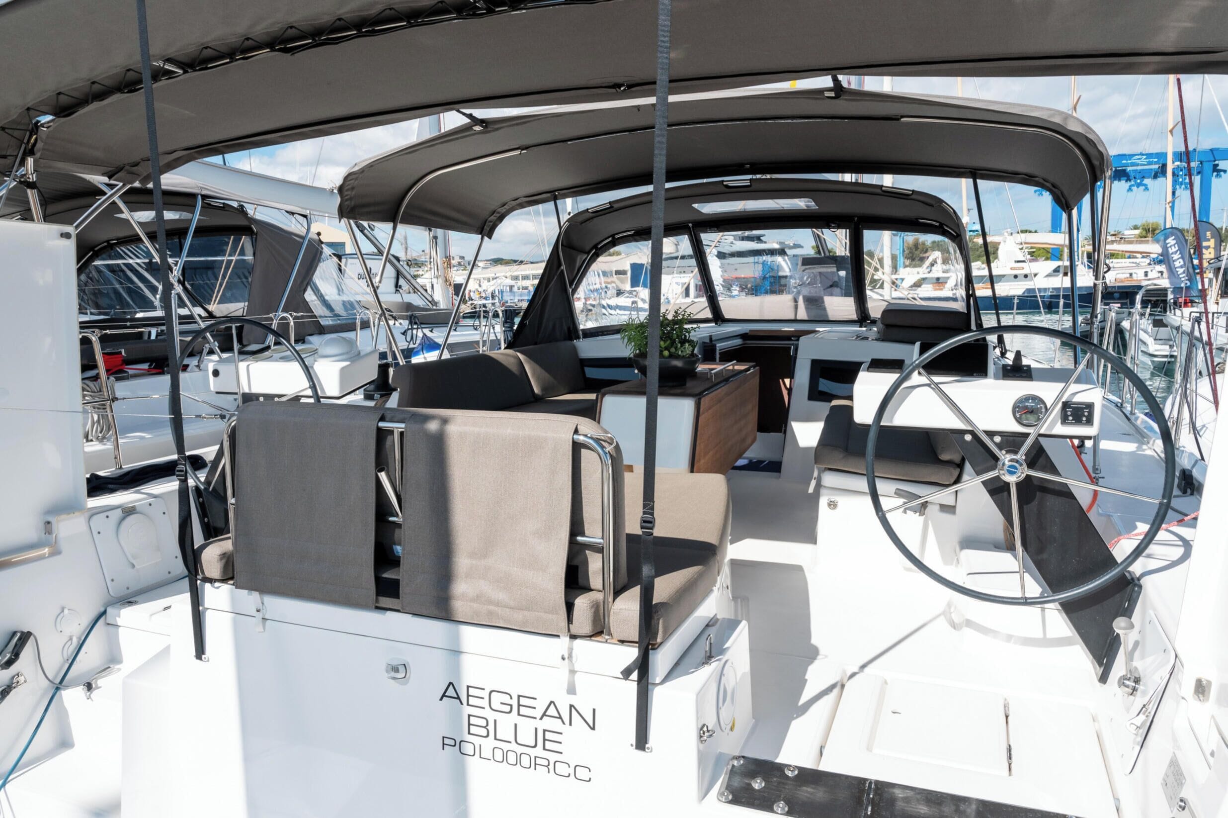 A yacht's interior with a steering wheel, cushioned seating, and a canopy.