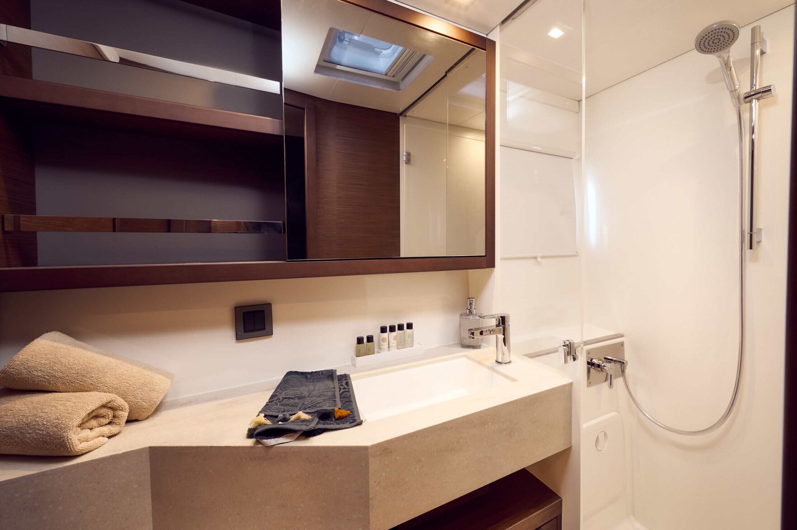 Un bagno moderno con uno specchio grande, una doccia e un mobile lavabo con asciugamani e articoli da toilette.