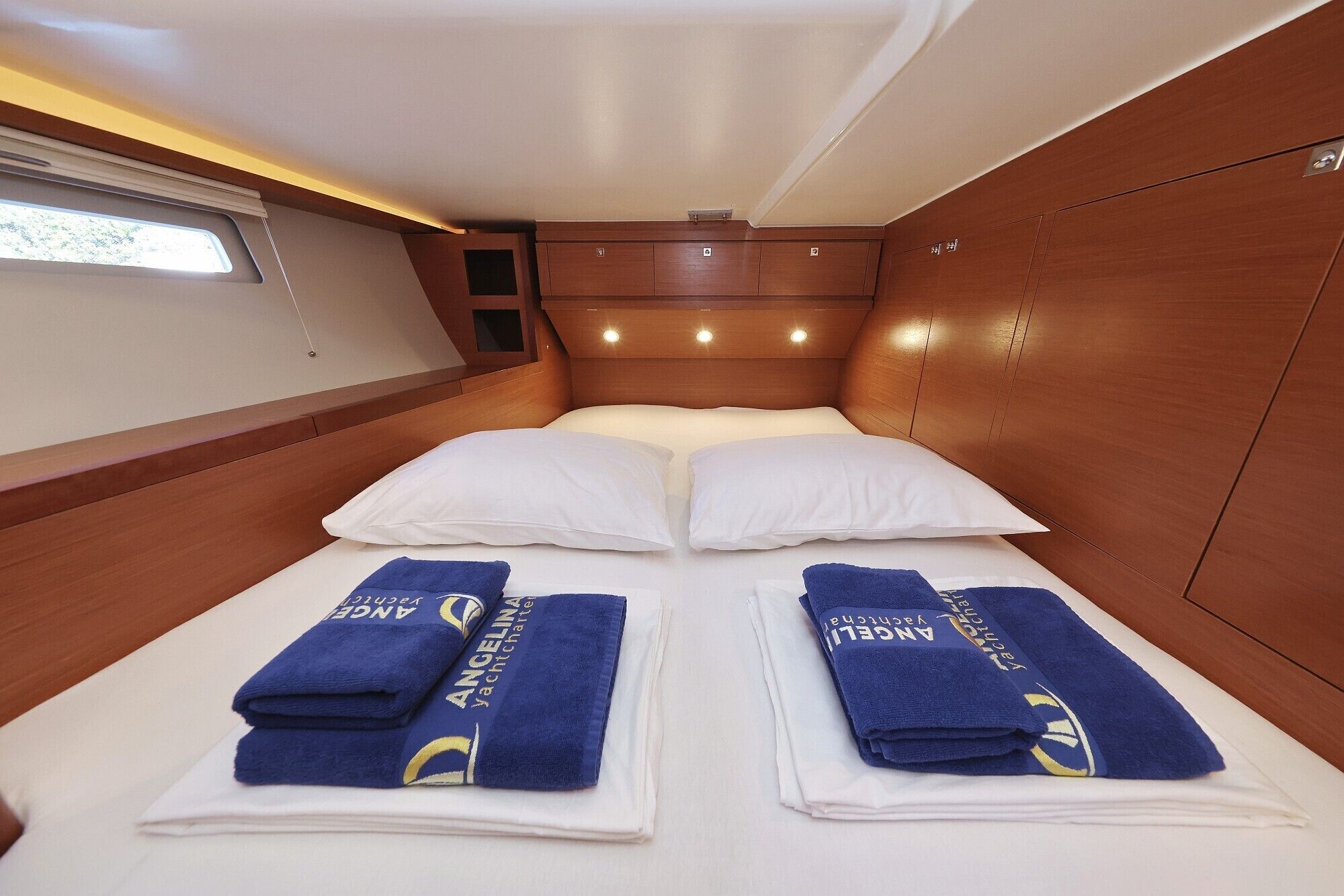 A cabin with a bed, two towels, and a window.