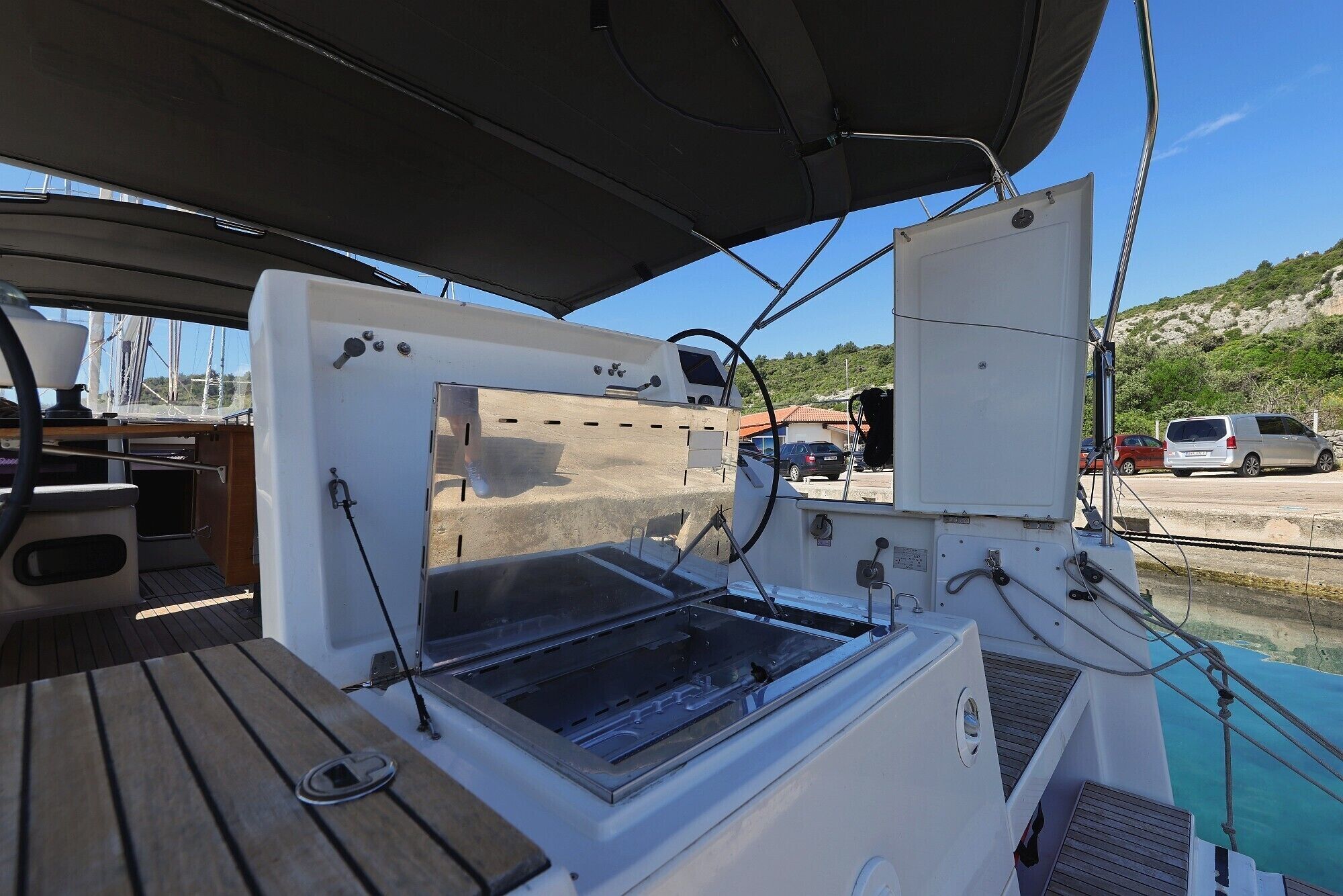 A boat's interior with a table, a window, and a view of the marina.