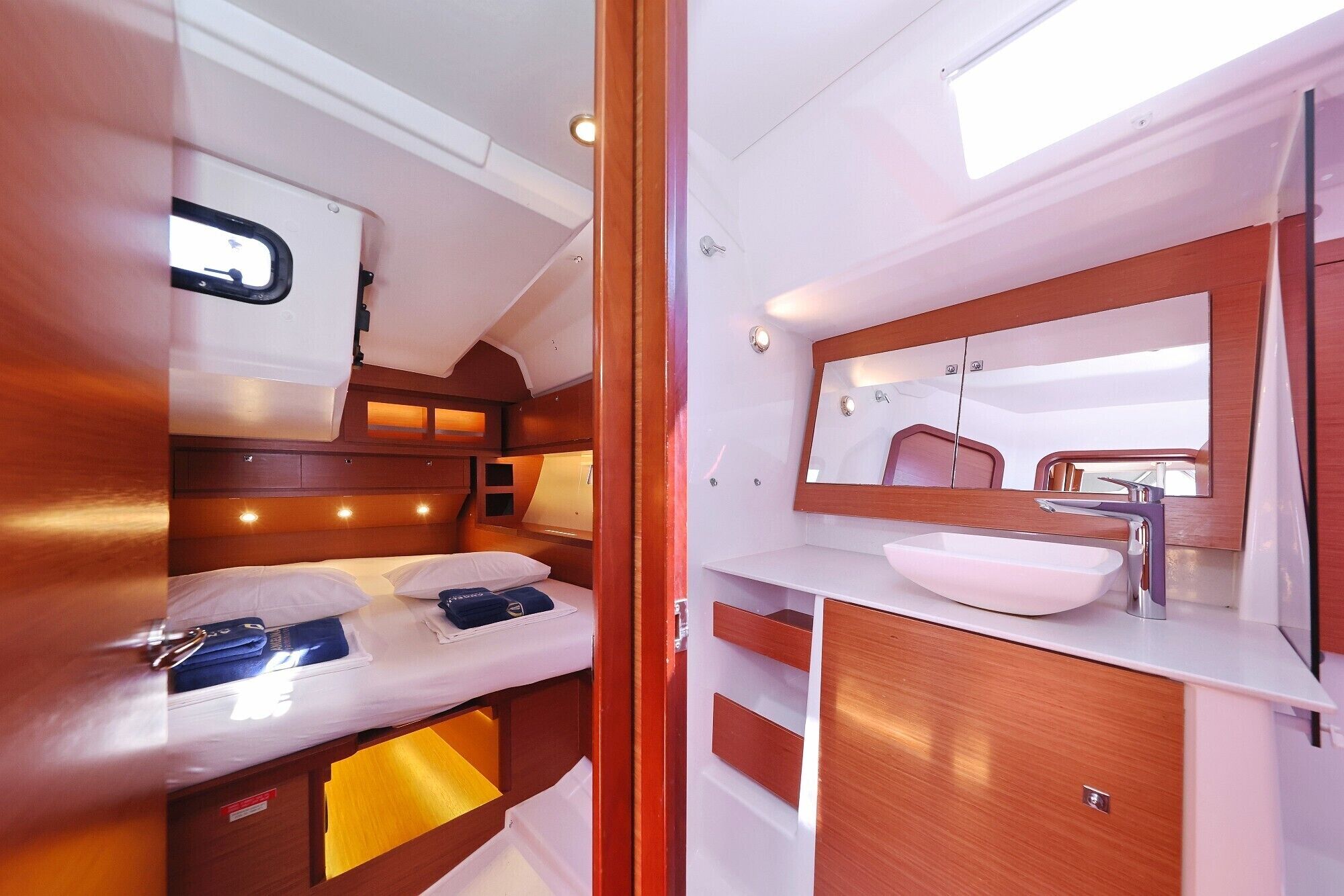 Une petite cabine comprenant un lit, une coiffeuse avec un miroir et une petite fenêtre.