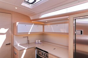Cocina compacta con horno integrado, lavamanos y alacenas superiores.