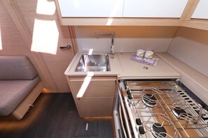 A compact kitchenette with a sink, stove, and a small seating area. - Sun-Kissed Sailing Adventure in Sibenik, Croatia (Primošten)