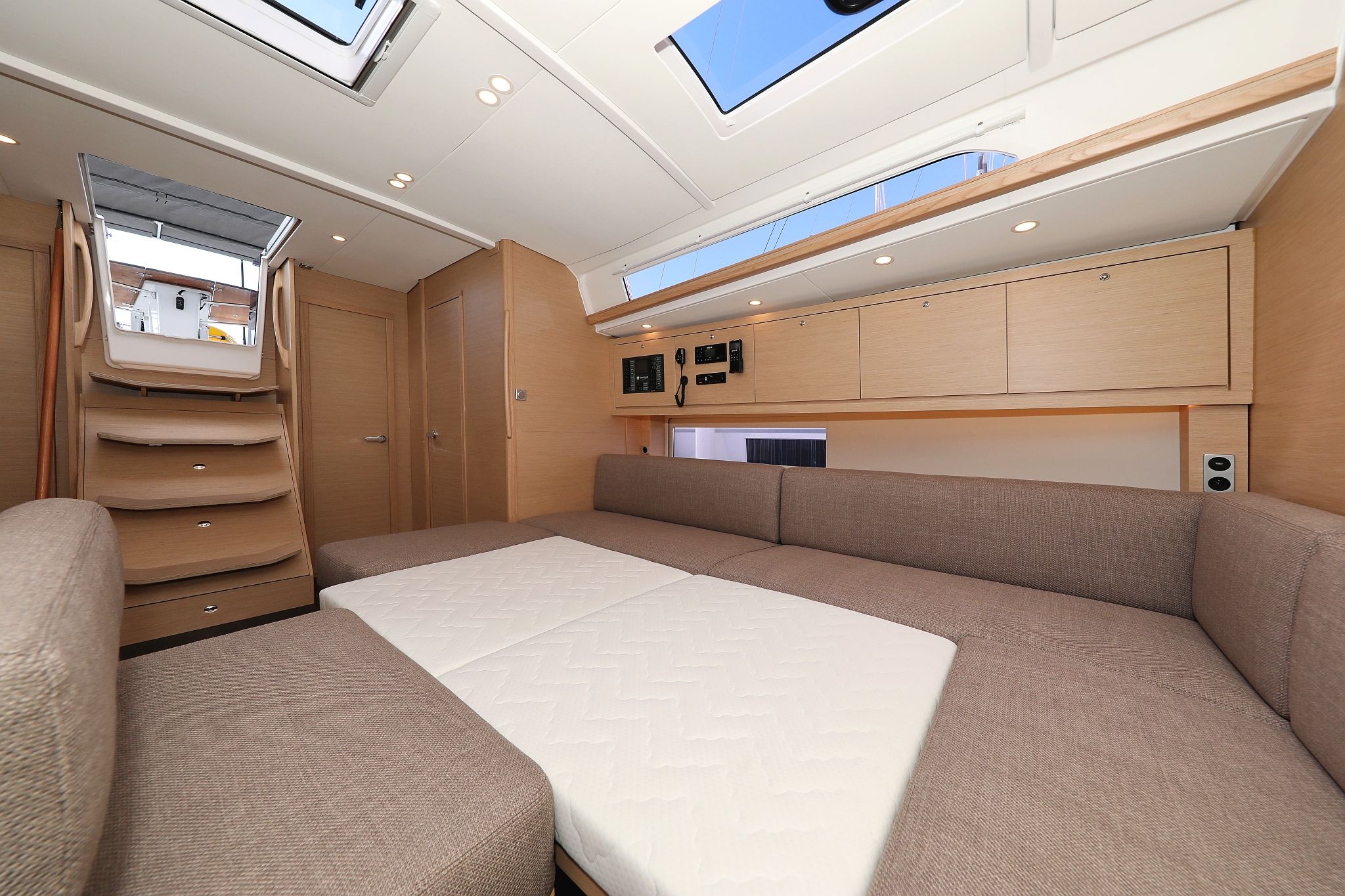 A compact interior with a bed, storage cabinets, and a skylight.