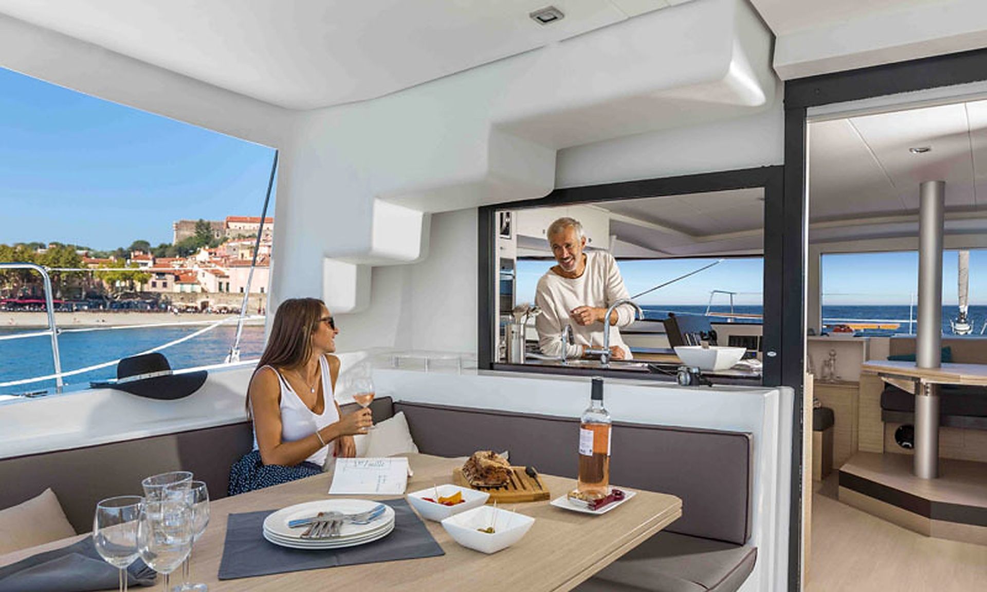 Un espace repas sur un yacht offrant une vue sur la mer et le paysage urbain.