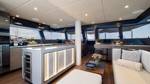 Un intérieur de yacht moderne comprenant une cuisine centrale, un coin repas et un espace salon.