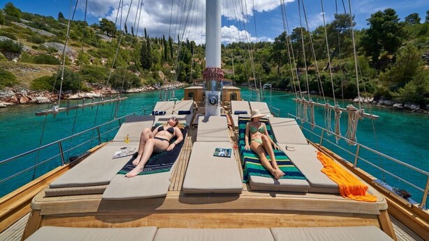A boat deck with lounge chairs, a mast, and a view of a turquoise sea and green hills. - Sun-Kissed Sailing Adventure in Split, Croatia (Split)