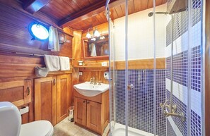 Et badeværelse i træ med toilet, vask og bruser.