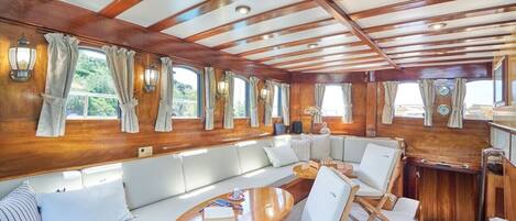 A cabin with a wooden ceiling, large windows, a sofa, and a table.