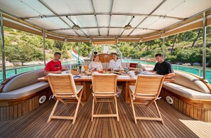 Un espacio de comedor techado con mobiliario de madera, una piscina y vistas panorámicas.