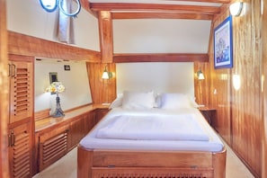 Quarto com painéis de madeira, uma cama, mesas de cabeceira e luminárias fixadas na parede.