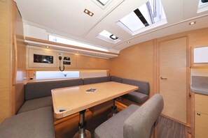 A compact, well-lit interior with a foldable table, cushioned seating, a control panel, and skylights. - Sun-kissed Sailing Adventure in Split-Dalmatia, Croatia (Trogir)