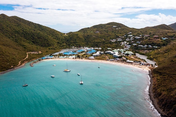 An aerial view of a coastal area with a beach, boats, and buildings.