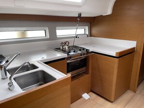 A compact kitchen with a gas stove, sink, and a window above the counter. - Sun-Kissed Sailing Adventure in the Sporades Islands from Volos, Thessaly (Volos)