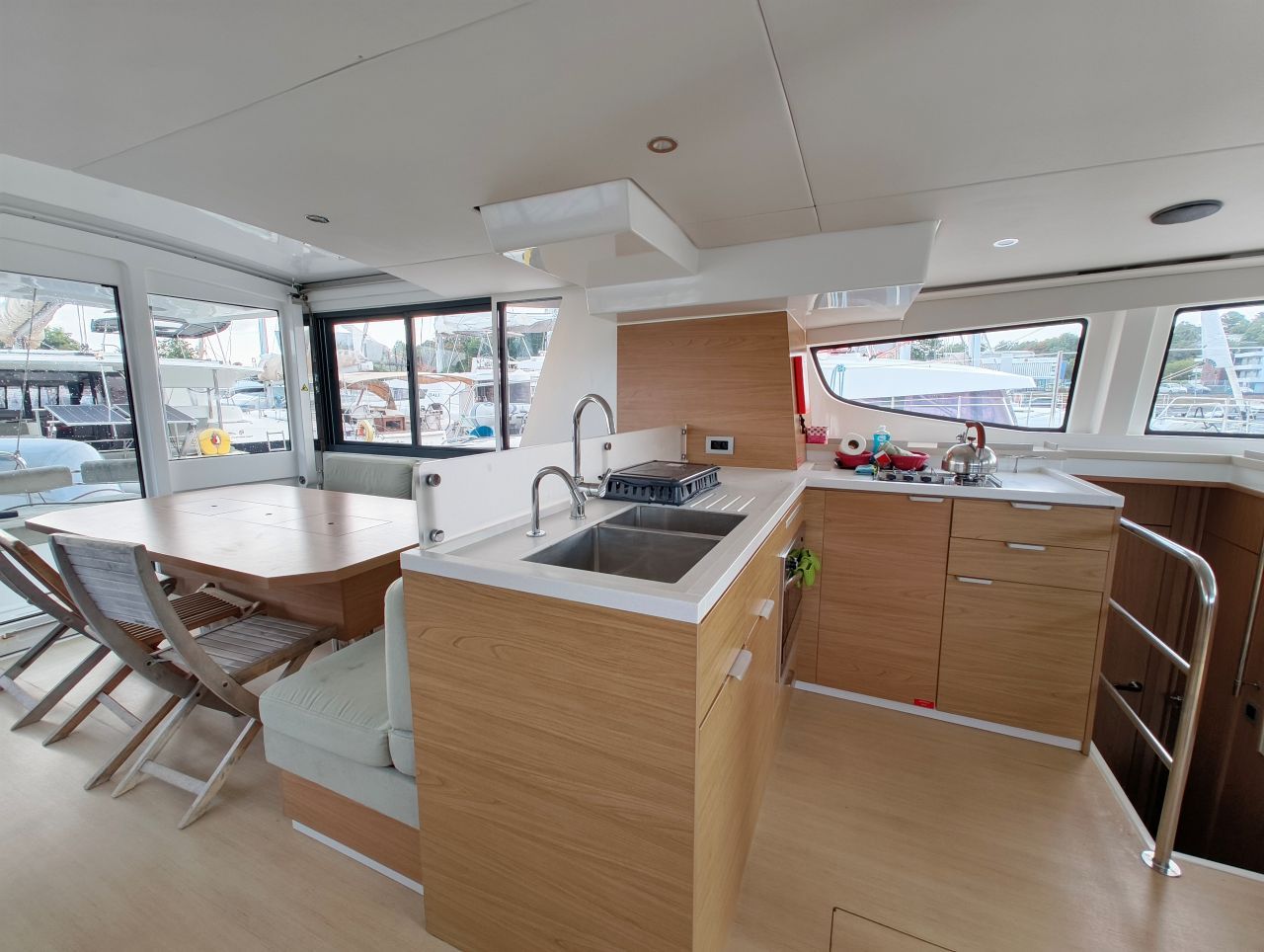 A modern kitchen with a central island, a dining area with chairs, and large windows offering views of the marina.