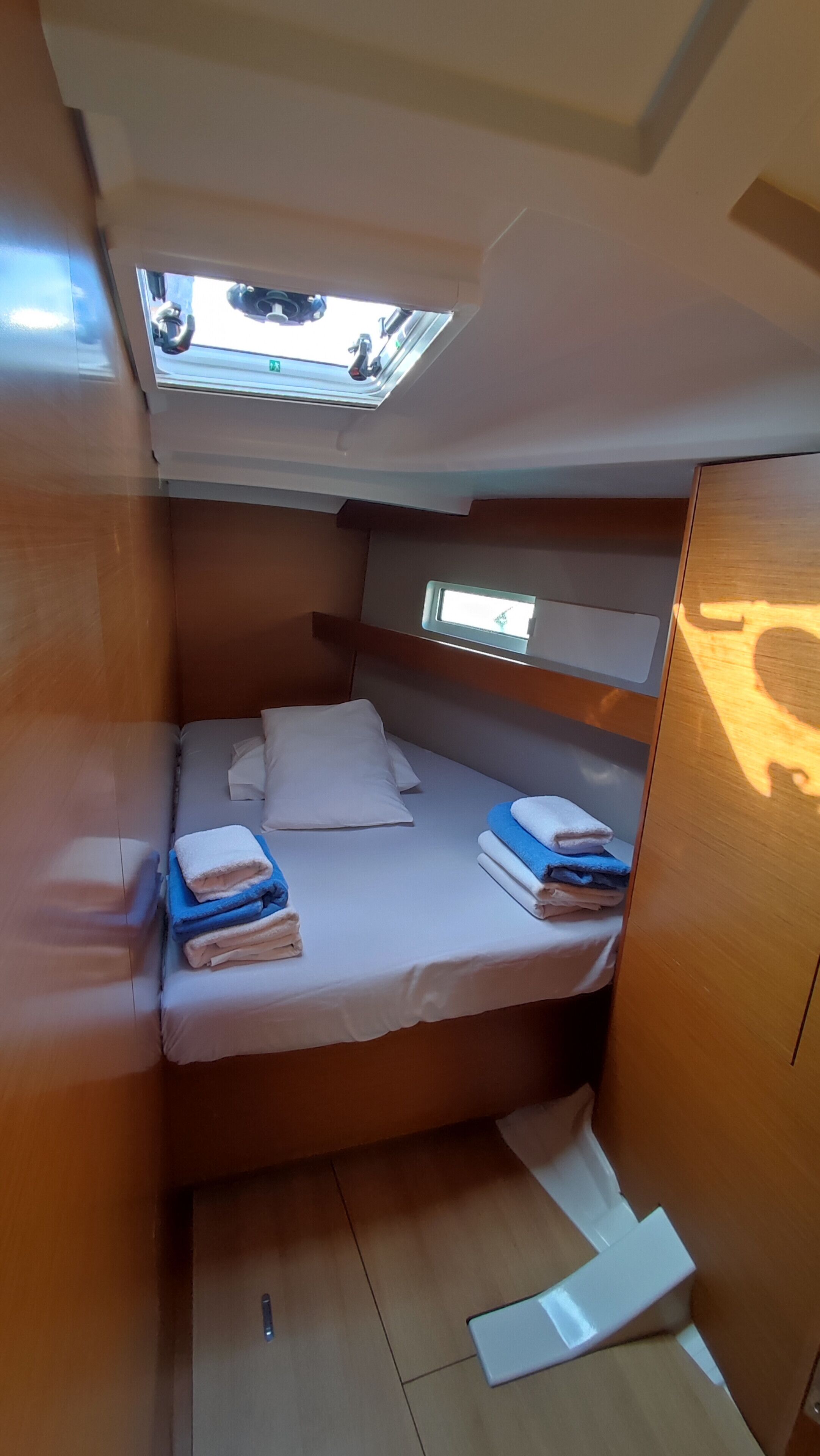 A compact cabin with a bunk bed, a skylight, and a small window.