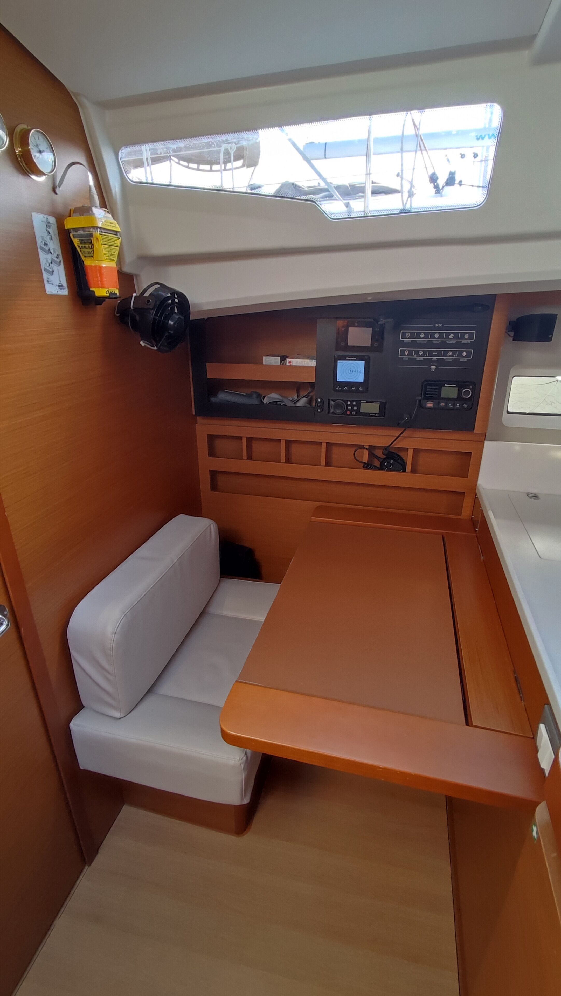 A compact interior with a cushioned seating area, a control panel with various dials and screens, and a window providing a view of the outside.