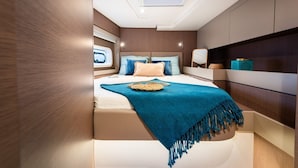 A bedroom with a skylight, a bed with a blue blanket, and a bedside table with decorative items.