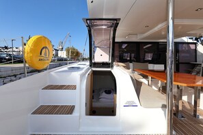 A yacht's deck with a covered seating area, a small enclosed space with a bed, and a yellow inflatable dinghy. - Sun-kissed Sailing Adventure in Split-Dalmatia, Croatia (Trogir)
