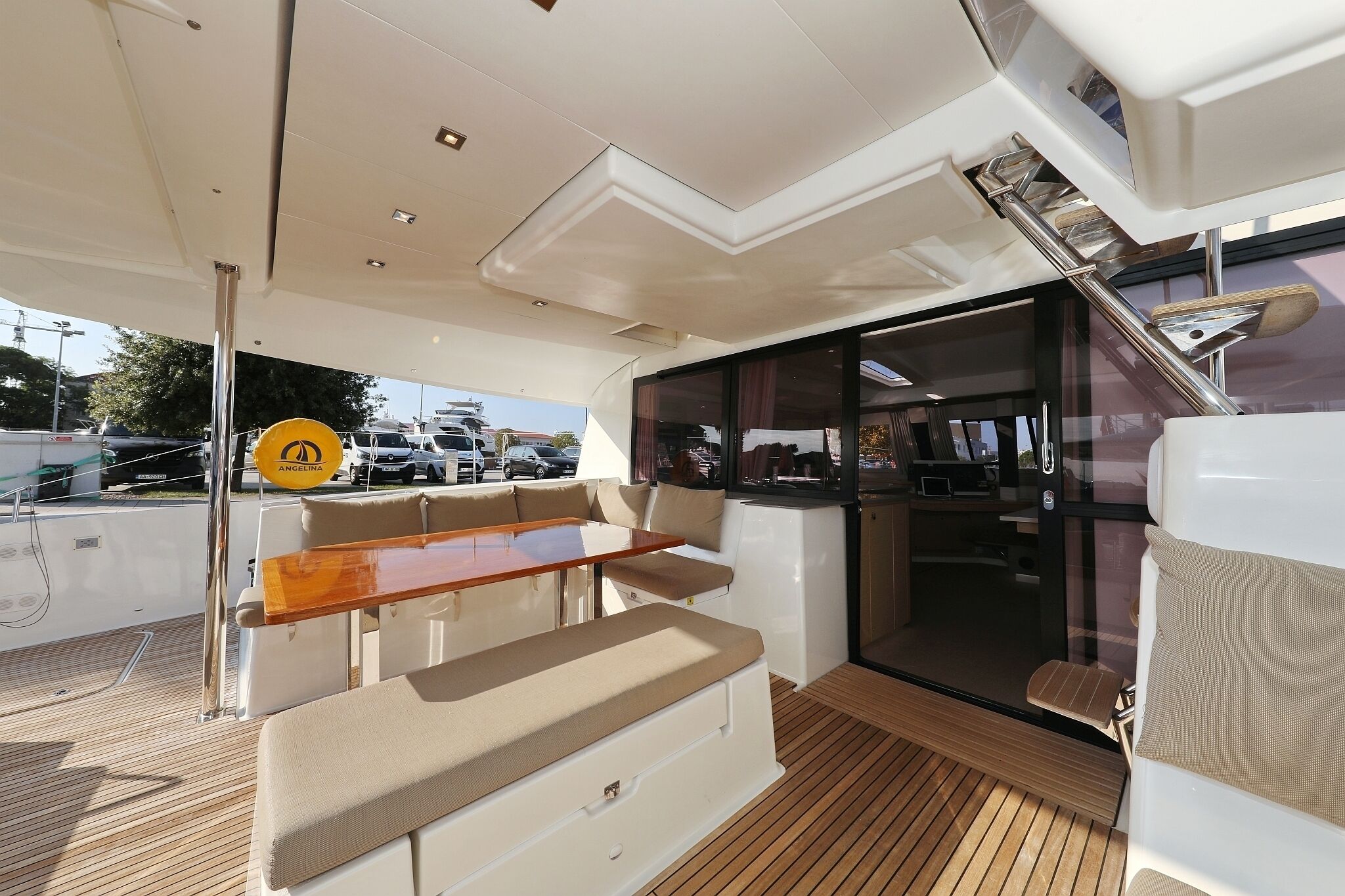 A yacht deck with a seating area, a glass door, and a staircase.